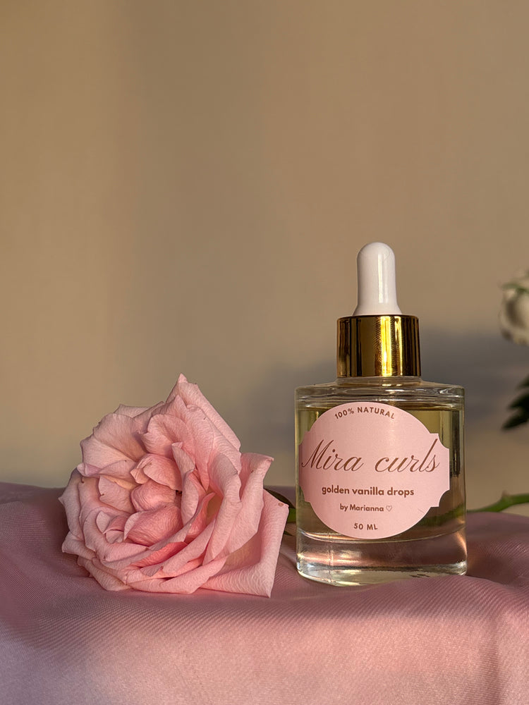 Mira Curls golden vanilla drops beside a pink rose